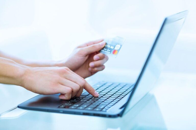 Immagine di una persona che tiene in mano una carta di credito e digita su un computer portatile per eseguire un pagamento anticipato online